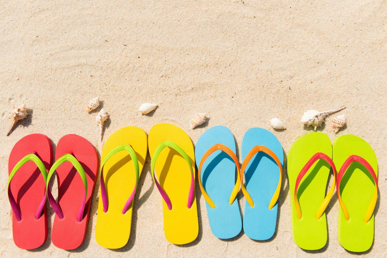Four pairs of flip flops in a row on beach