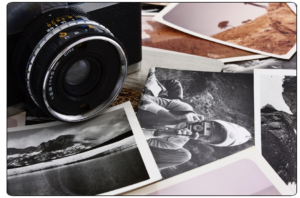 35mm camera and old b+w photos on wooden table
